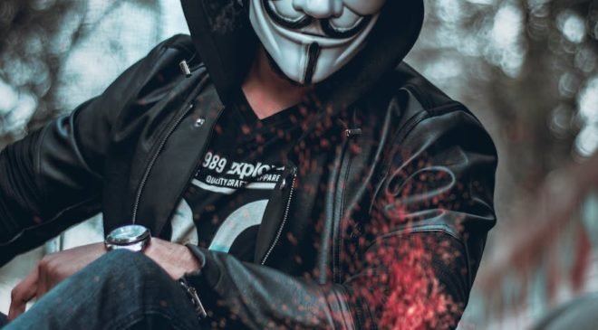 person wearing guys fawkes mask watching flame